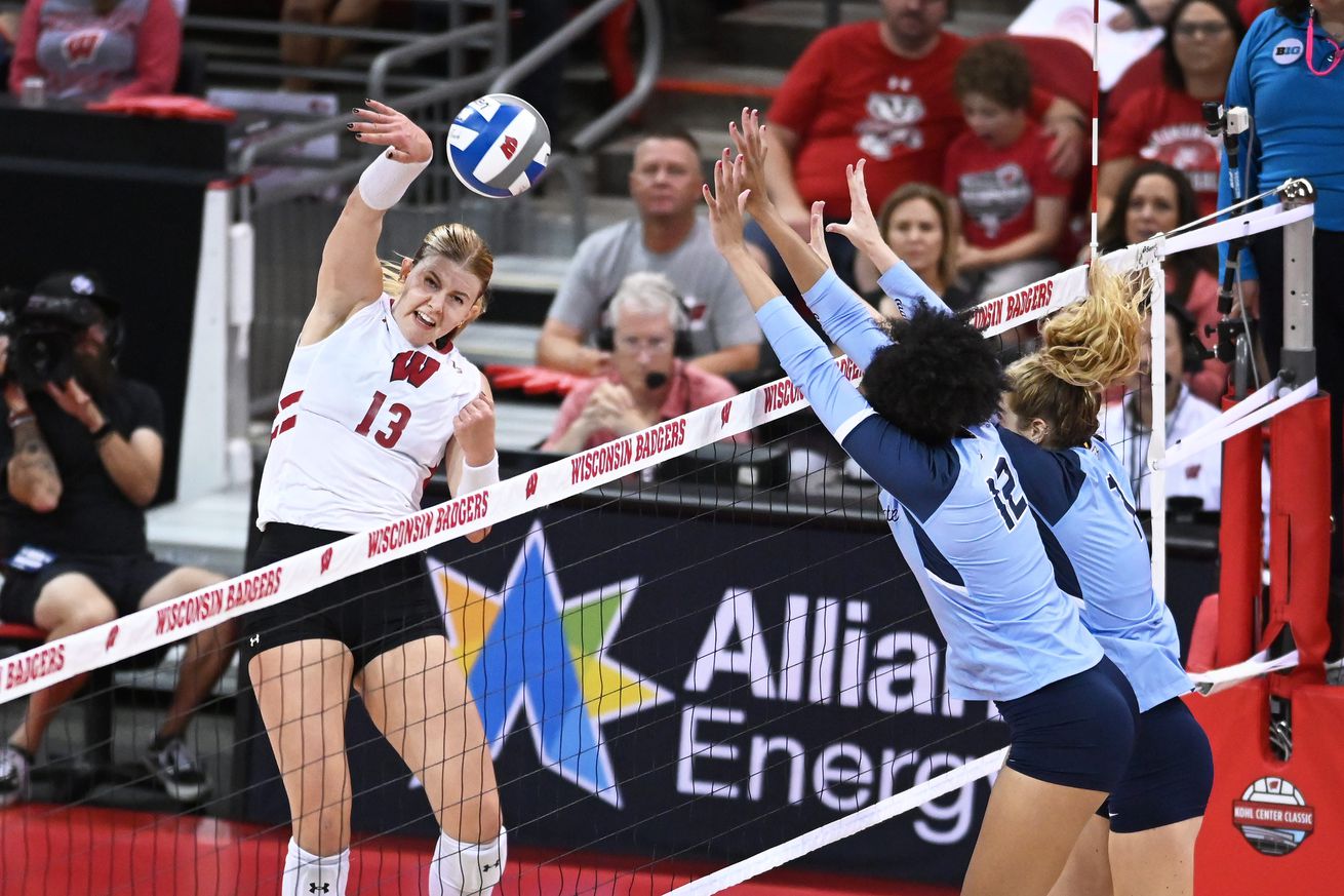 Wisconsin outside hitter Sarah Franklin (13) hits around the Marquette block of Marquette middle blocker Carsen Murray (12) and right side hitter/setter Ella Foti (7) in a match Tuesday, September 17, 2024, at the Kohl Center in Madison, Wisconsin. 