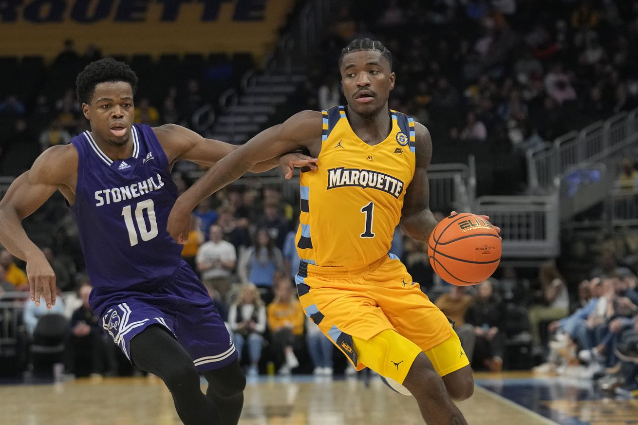 Kam Jones #1 of the Marquette Golden Eagles dribbles the ball against Hermann Koffi #10 of the Stonehill Skyhawks during the first half at Fiserv Forum on November 27, 2024 in Milwaukee, Wisconsin.