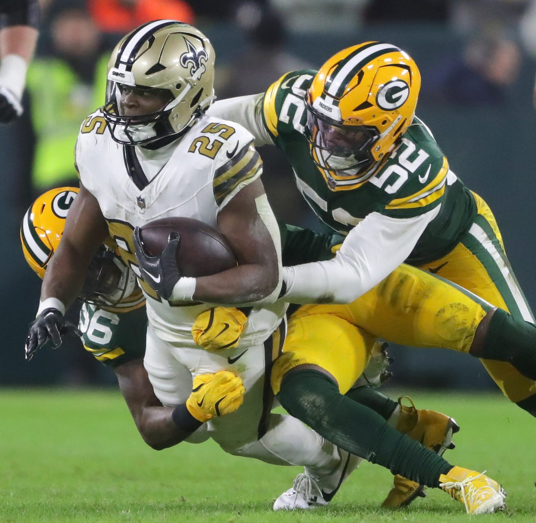 Green Bay Packers defensive end Rashan Gary (52) and linebacker Edgerrin Cooper (56) tackle New Orleans Saints running back Kendre Miller (25) on Monday